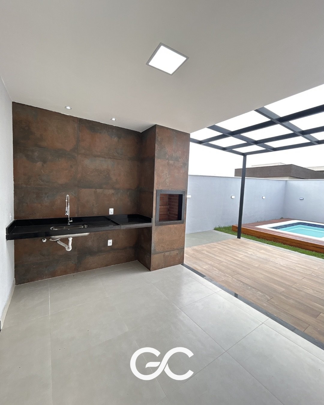 Espaço gourmet com churrasqueira, bancada e vista para a piscina no Alphaville 1